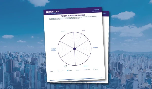 Two printed worksheets titled 'FORBES MOMENTUM TRACKER' and 'MOMENTORS' with a circular chart, placed against a city skyline background with blue sky and clouds.