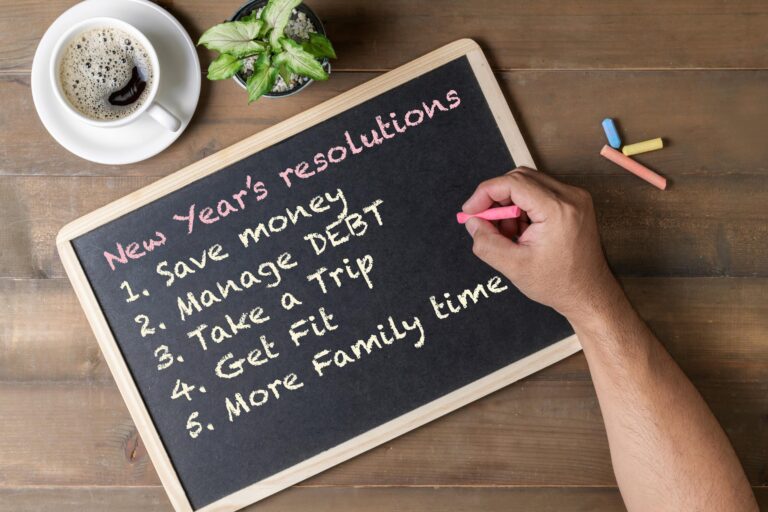 a man's hand writing new years resolutions on a chalk board