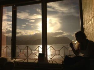 A man praying in front of a window as the sun rises