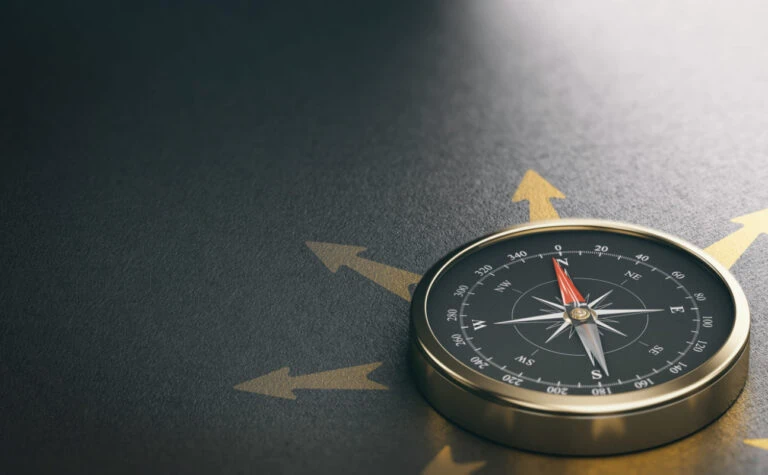 A compass on a dark surface with multiple arrows pointing in different directions, symbolizing guidance and direction.